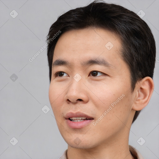 Joyful asian young-adult male with short  brown hair and brown eyes