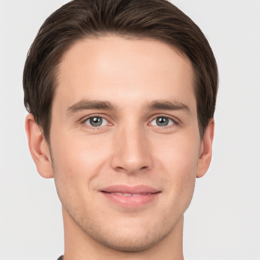 Joyful white young-adult male with short  brown hair and grey eyes