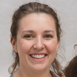 Joyful white young-adult female with medium  brown hair and grey eyes