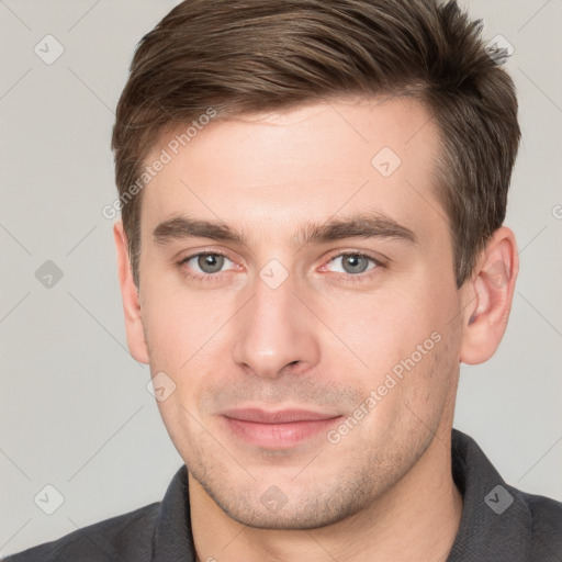 Joyful white young-adult male with short  brown hair and grey eyes