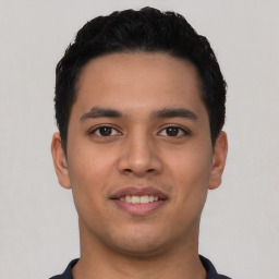 Joyful latino young-adult male with short  black hair and brown eyes