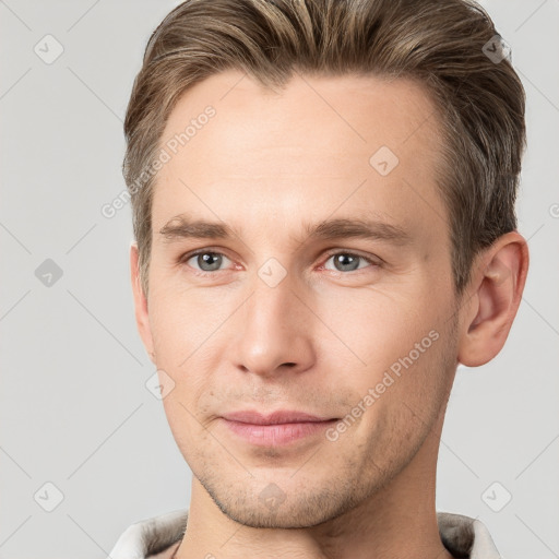 Joyful white young-adult male with short  brown hair and grey eyes