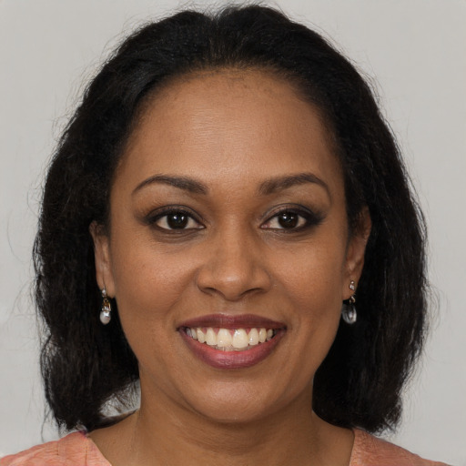 Joyful black young-adult female with long  brown hair and brown eyes