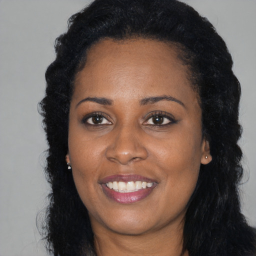 Joyful black young-adult female with long  black hair and brown eyes
