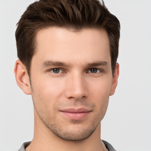 Joyful white young-adult male with short  brown hair and grey eyes