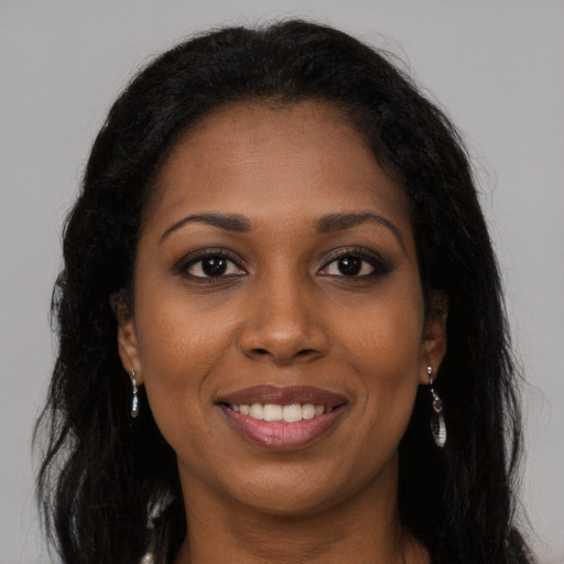 Joyful black young-adult female with long  brown hair and brown eyes