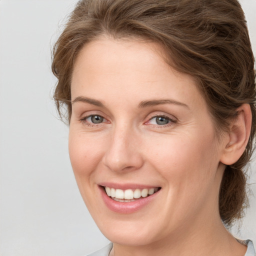 Joyful white young-adult female with medium  brown hair and grey eyes