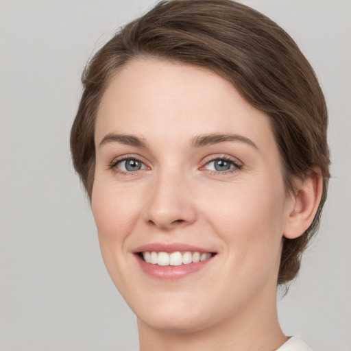 Joyful white young-adult female with short  brown hair and grey eyes