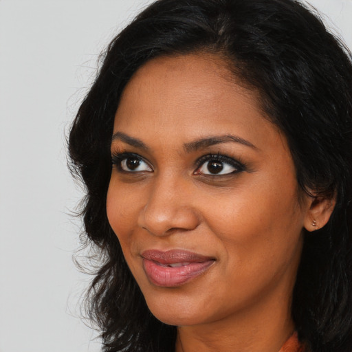 Joyful black young-adult female with long  brown hair and brown eyes