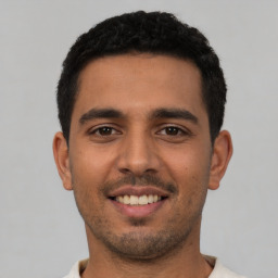 Joyful latino young-adult male with short  black hair and brown eyes