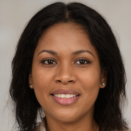 Joyful black young-adult female with long  brown hair and brown eyes