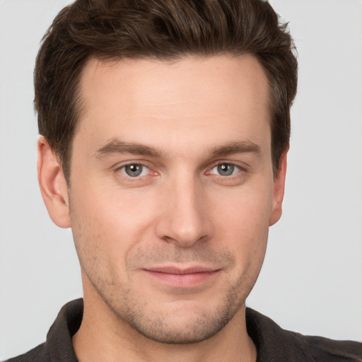 Joyful white young-adult male with short  brown hair and grey eyes