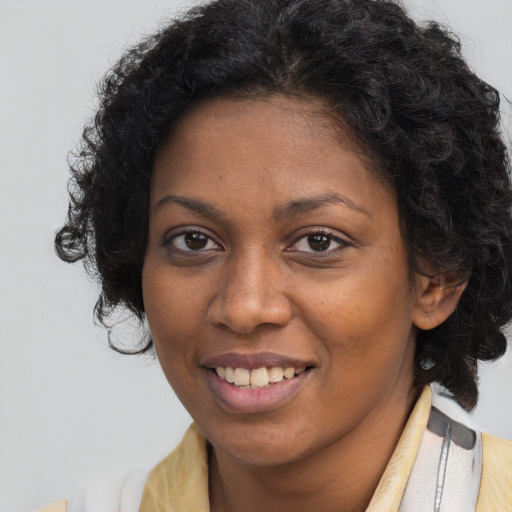 Joyful black young-adult female with long  brown hair and brown eyes