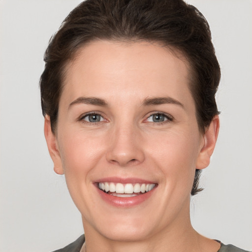 Joyful white young-adult female with short  brown hair and grey eyes