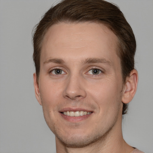 Joyful white young-adult male with short  brown hair and grey eyes