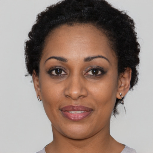 Joyful black young-adult female with short  black hair and brown eyes