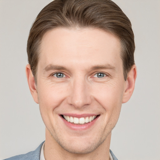 Joyful white young-adult male with short  brown hair and grey eyes