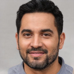 Joyful latino young-adult male with short  black hair and brown eyes