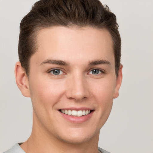 Joyful white young-adult male with short  brown hair and grey eyes