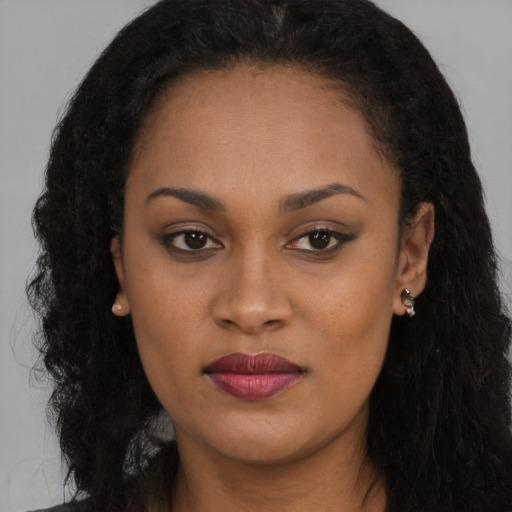 Joyful black young-adult female with long  brown hair and brown eyes
