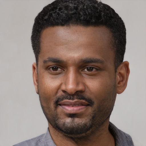 Joyful black young-adult male with short  black hair and brown eyes