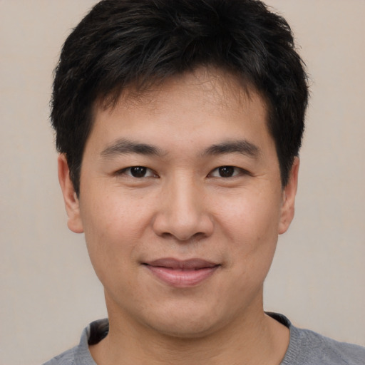 Joyful asian young-adult male with short  black hair and brown eyes