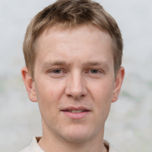 Joyful white young-adult male with short  brown hair and grey eyes