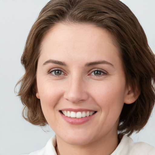 Joyful white young-adult female with medium  brown hair and grey eyes