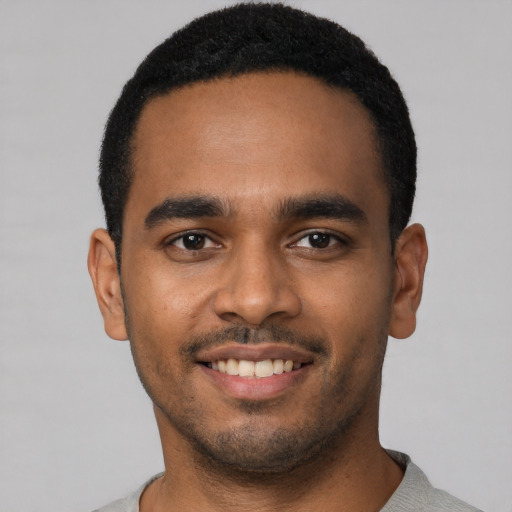 Joyful black young-adult male with short  black hair and brown eyes