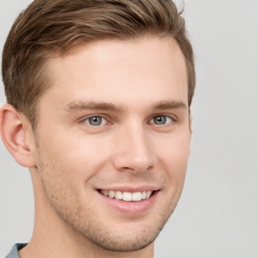 Joyful white young-adult male with short  brown hair and grey eyes