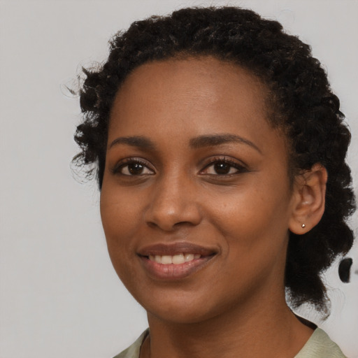 Joyful black young-adult female with long  black hair and brown eyes