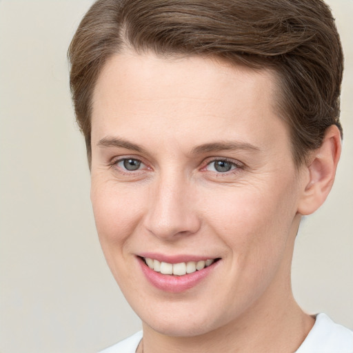 Joyful white young-adult female with short  brown hair and grey eyes