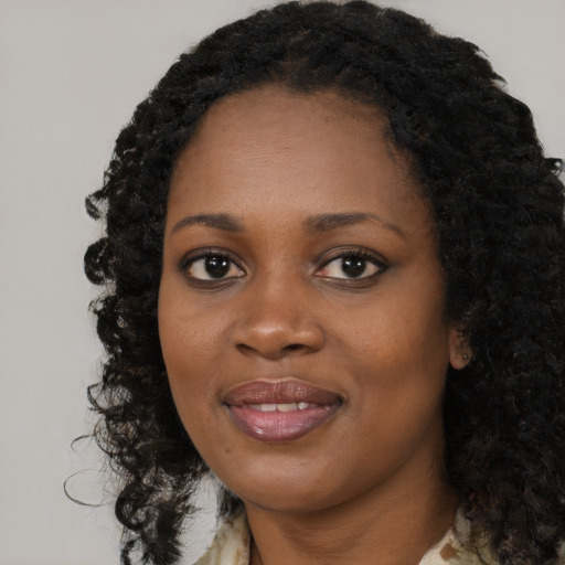 Joyful black young-adult female with long  black hair and brown eyes