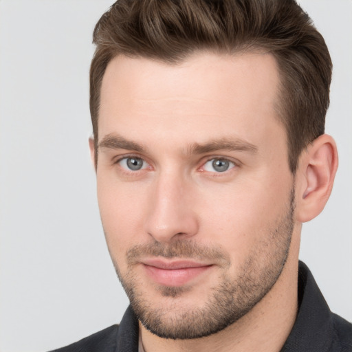 Joyful white young-adult male with short  brown hair and grey eyes