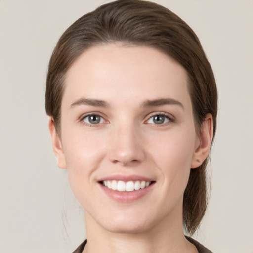 Joyful white young-adult female with medium  brown hair and grey eyes