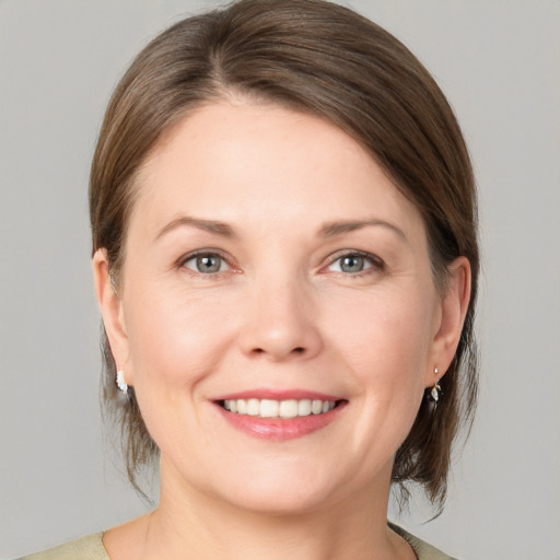 Joyful white young-adult female with medium  brown hair and grey eyes