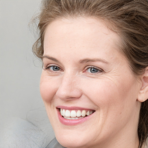 Joyful white young-adult female with medium  brown hair and blue eyes