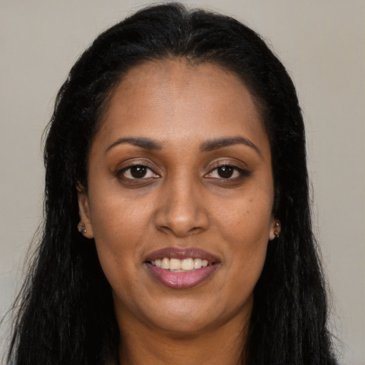 Joyful black young-adult female with long  black hair and brown eyes