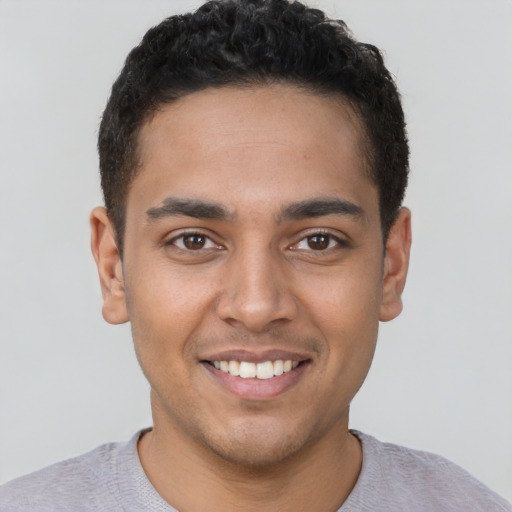 Joyful latino young-adult male with short  brown hair and brown eyes
