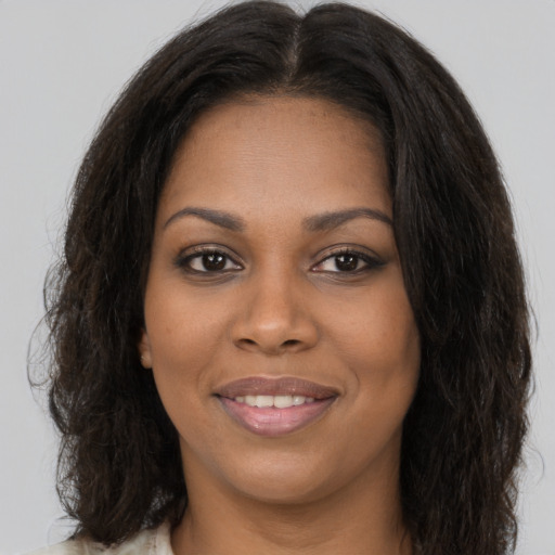 Joyful black young-adult female with long  brown hair and brown eyes