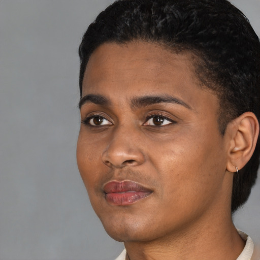 Joyful black young-adult female with short  black hair and brown eyes
