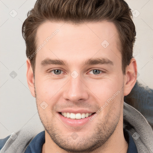 Joyful white young-adult male with short  brown hair and grey eyes