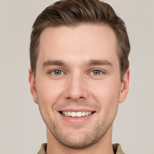 Joyful white young-adult male with short  brown hair and grey eyes