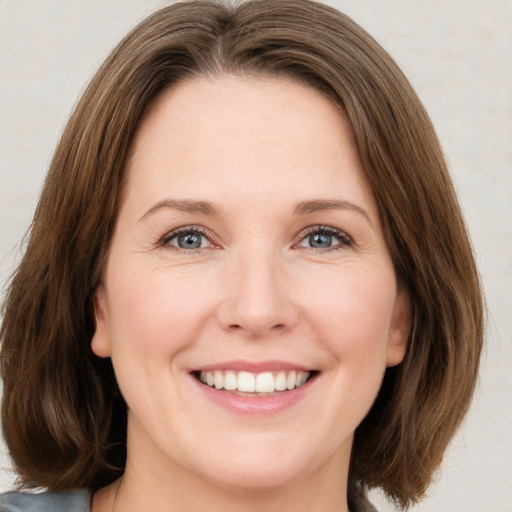 Joyful white young-adult female with medium  brown hair and green eyes