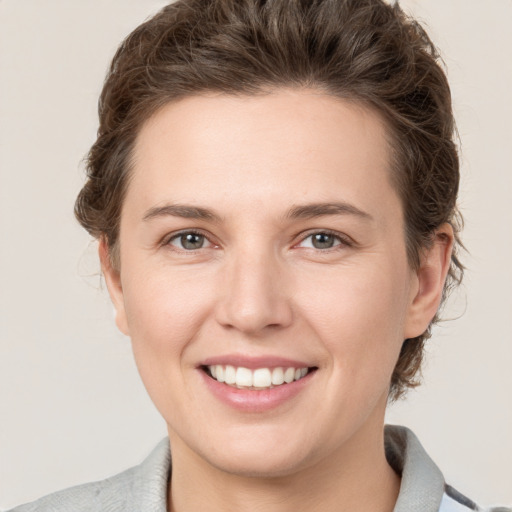 Joyful white young-adult female with short  brown hair and grey eyes