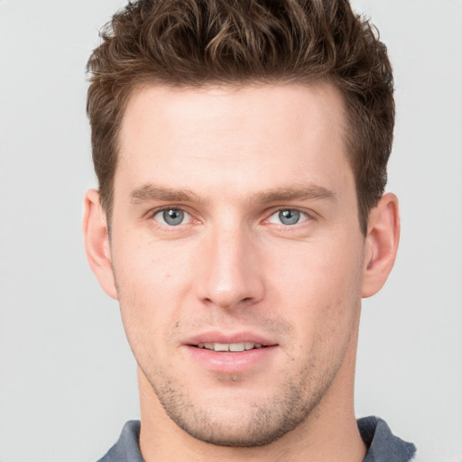 Joyful white young-adult male with short  brown hair and grey eyes