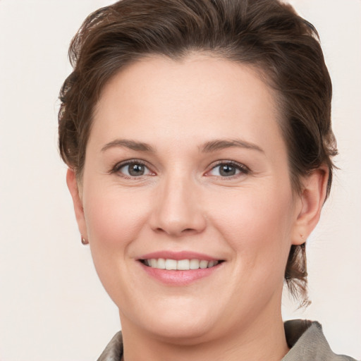 Joyful white young-adult female with medium  brown hair and grey eyes