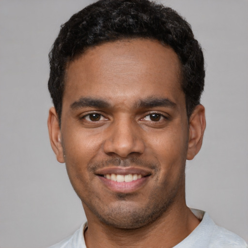 Joyful black young-adult male with short  black hair and brown eyes
