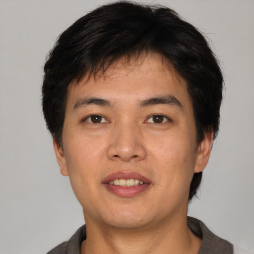 Joyful asian young-adult male with short  brown hair and brown eyes