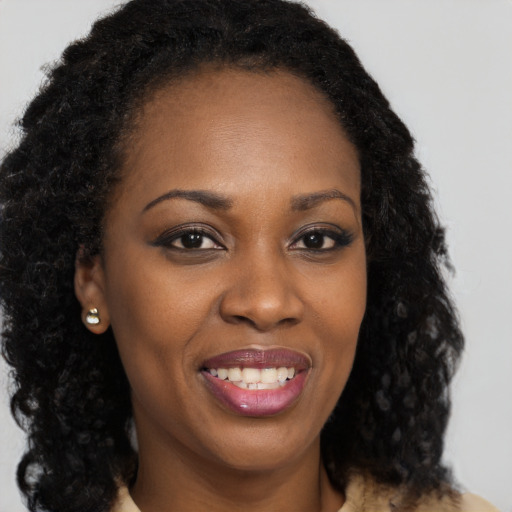 Joyful black young-adult female with long  brown hair and brown eyes
